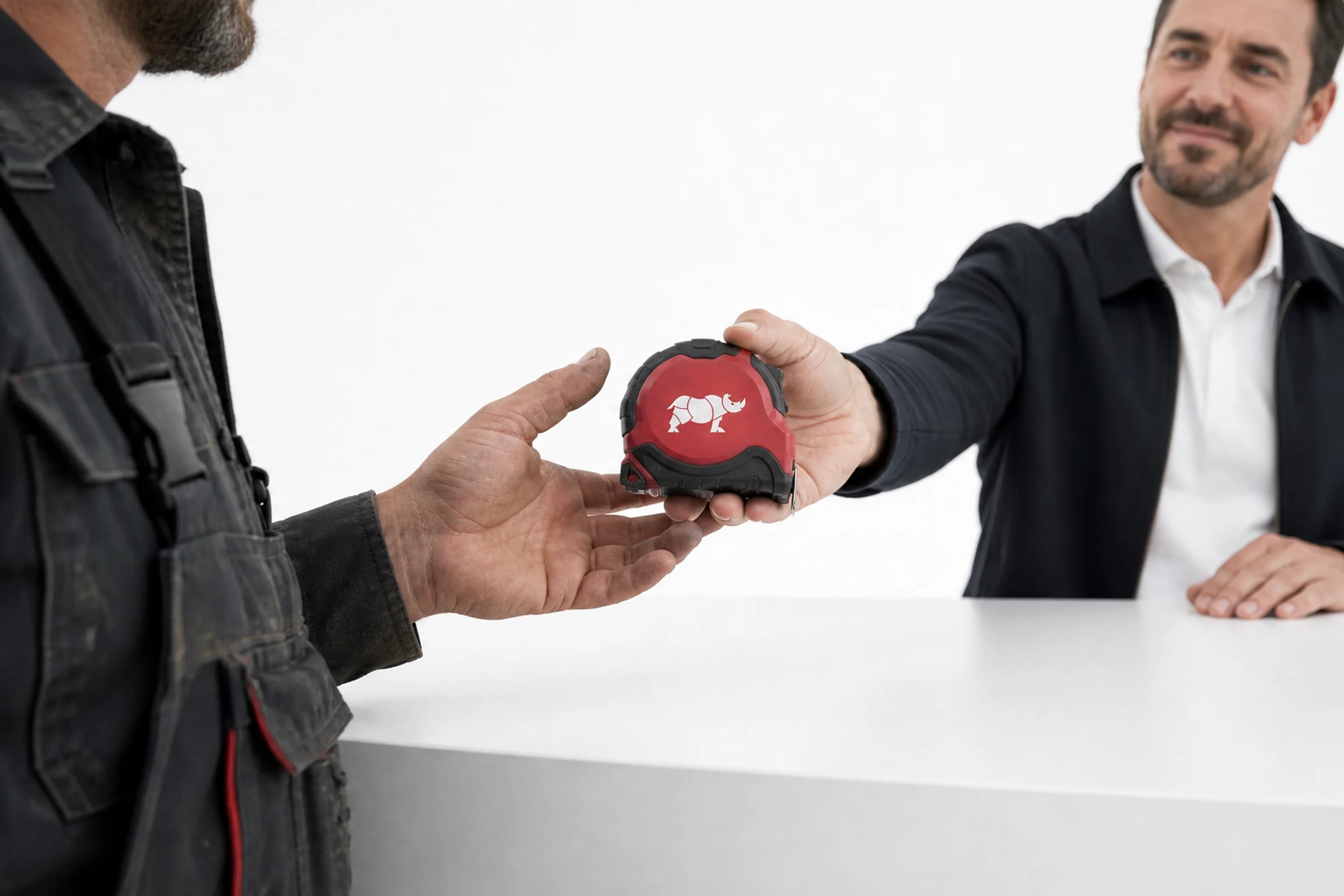 Dispositif distributeurs : au comptoir, un artisan reçoit un mètre ruban rouge Groupe Rhinos en récompense